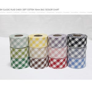May include: Twelve rolls of 10mm soft cotton bias tape in a classic plaid check pattern. Colors include green, yellow, purple, pink, and blue. The text at the top reads "NEW CLASSIC PLAID CHECK SOFT COTTON 10mm BIAS 12COLOR CHART."
