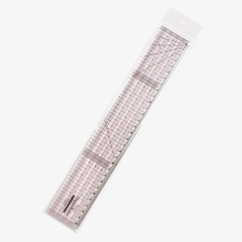 Puede incluir: Una regla de pl&aacute;stico transparente con l&iacute;neas de cuadr&iacute;cula rosas y medidas. La regla est&aacute; empaquetada en una funda de pl&aacute;stico transparente. El texto "Happy Ruler" est&aacute; impreso en la regla. Ideal para proyectos de costura y manualidades.