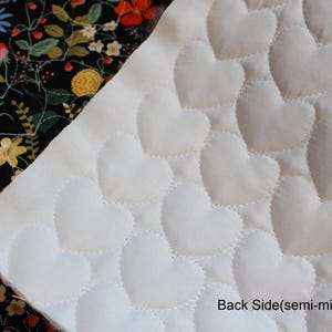 Pu&ograve; includere: Un pezzo di tessuto con un lato bianco caratterizzato da un motivo a cuori trapuntati e un lato nero con una stampa floreale colorata con fiori rossi, gialli e blu. Il testo Back Side(semi-micro Fabric) &egrave; stampato nell'angolo in basso a destra.
