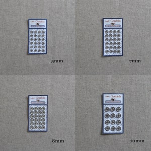 May include: Four packs of silver metal snap fasteners in different sizes: 5mm, 7mm, 8mm, and 10mm. Each pack has a white label with the brand name "Gondola" and the size of the fasteners printed on it.