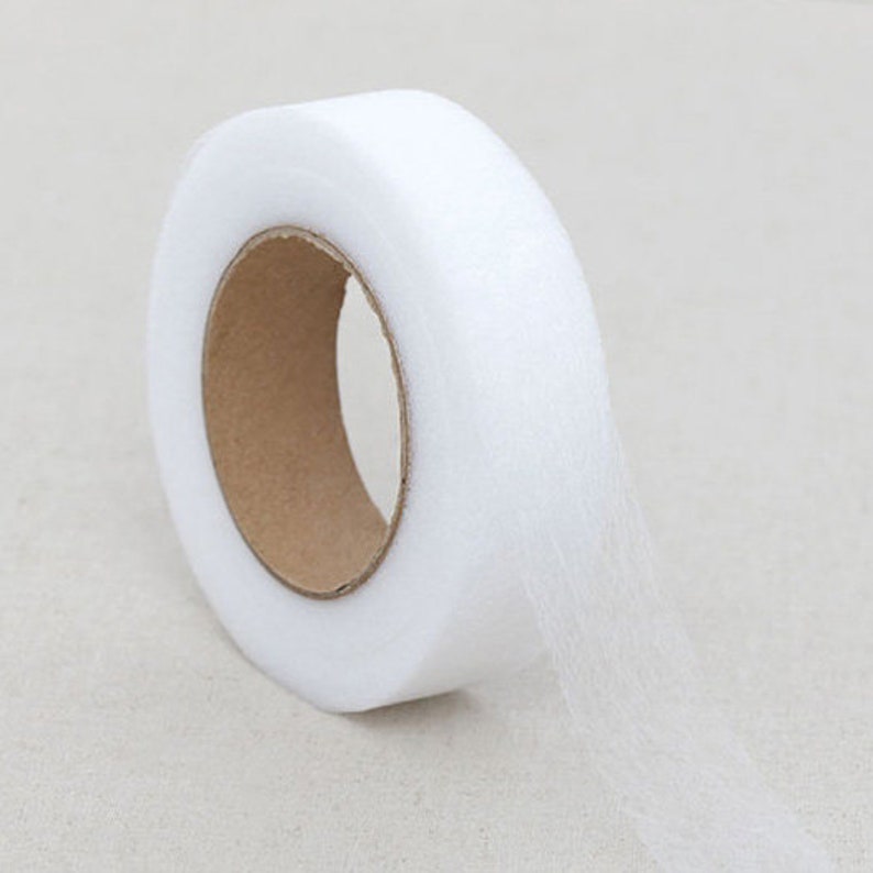May include: A roll of white tulle fabric. The tulle is tightly wound around a cardboard core, with a portion of the fabric unrolled, revealing its delicate, sheer texture. The fabric is ideal for crafting, sewing, and decorative projects.