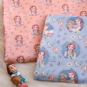 May include: Two pieces of fabric with a repeating pattern of Belle from Beauty and the Beast. The fabric on the left is peach with a white floral pattern and the fabric on the right is light blue with a white floral pattern. Both fabrics have the text "wash with your heart" on them.