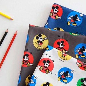 Puede incluir: Cuatro muestras de tela diferentes que presentan un patrón repetido de Mickey Mouse en varias poses. Las muestras de tela son de color azul marino, gris, blanco y verde.