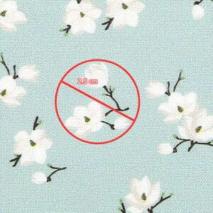 May include: A light blue fabric featuring a repeating pattern of white flowers with dark brown stems and yellow centers. A red circle overlays the fabric, containing a line with the text 2.5 cm, indicating the scale of the floral pattern.