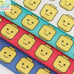 Peut inclure: Quatre échantillons de tissu avec un motif répété de têtes de Lego jaunes souriantes sur des fonds de couleurs différentes. Les couleurs sont le blanc, le turquoise, le rouge et le bleu.