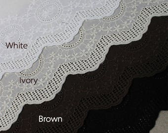 Peut inclure: Quatre échantillons de dentelle dans différentes couleurs : blanc, ivoire, marron et noir. La dentelle est un motif délicat et festonné avec un motif répétitif de cercles et de fleurs.