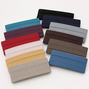 May include: A collection of rectangular fabric swatches arranged in a fan-like pattern. The swatches feature a variety of solid colors including black, navy, gray, brown, blue, beige, yellow, light pink, red, purple, and teal, each with a textured finish.