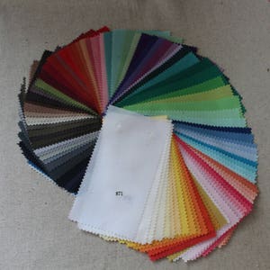Puede incluir: Un libro de muestras de tela con una variedad de colores, incluyendo rojo, verde, azul, amarillo y blanco. Las muestras est&aacute;n dispuestas en forma de abanico, con la muestra blanca en el centro. El texto "871" est&aacute; impreso en la muestra blanca.