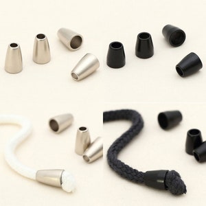 May include: Assortment of silver and black cord end stoppers. The stoppers are shown on a white surface and on a white and gray cord.