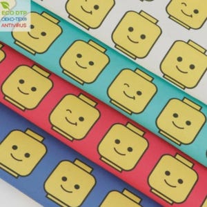 Peut inclure: Motif répété de visages jaunes de style Lego avec des yeux et des sourires noirs sur divers fonds colorés. Les fonds comprennent le blanc, le turquoise, le rouge et le bleu. L'image comprend également le texte "ECO DTP OEKO-TEX® ANTIVIRUS".