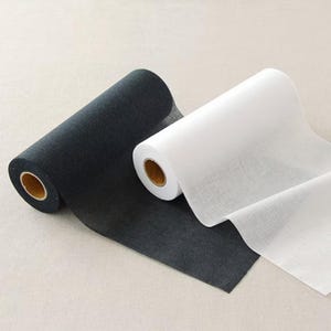 May include: Two rolls of fabric, one black and one white, are displayed. The black roll is unrolled slightly, revealing a textured surface. The white roll is also partially unrolled, showing a smooth, translucent material. Both rolls have a cardboard core.