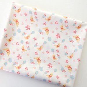 May include: White fabric with a repeating pattern of Winnie the Pooh characters holding balloons, pink flowers, and light blue balloons. The fabric is suitable for various crafting projects.