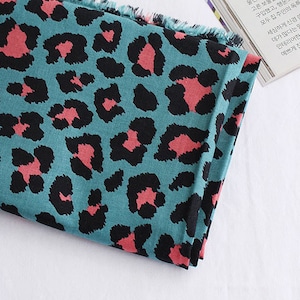 May include: Teal fabric with a pink and black leopard print pattern.