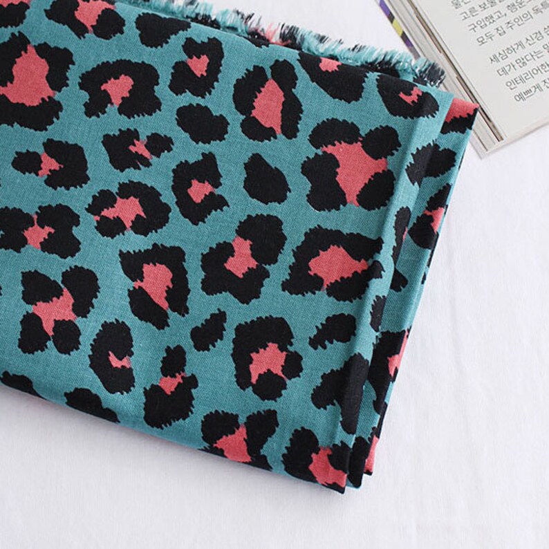 May include: Teal fabric with a pink and black leopard print pattern.