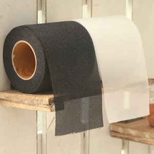 May include: A roll of black and white mesh fabric. The fabric is rolled up and secured with a brown cardboard tube. The fabric is textured and has a slightly shiny finish.