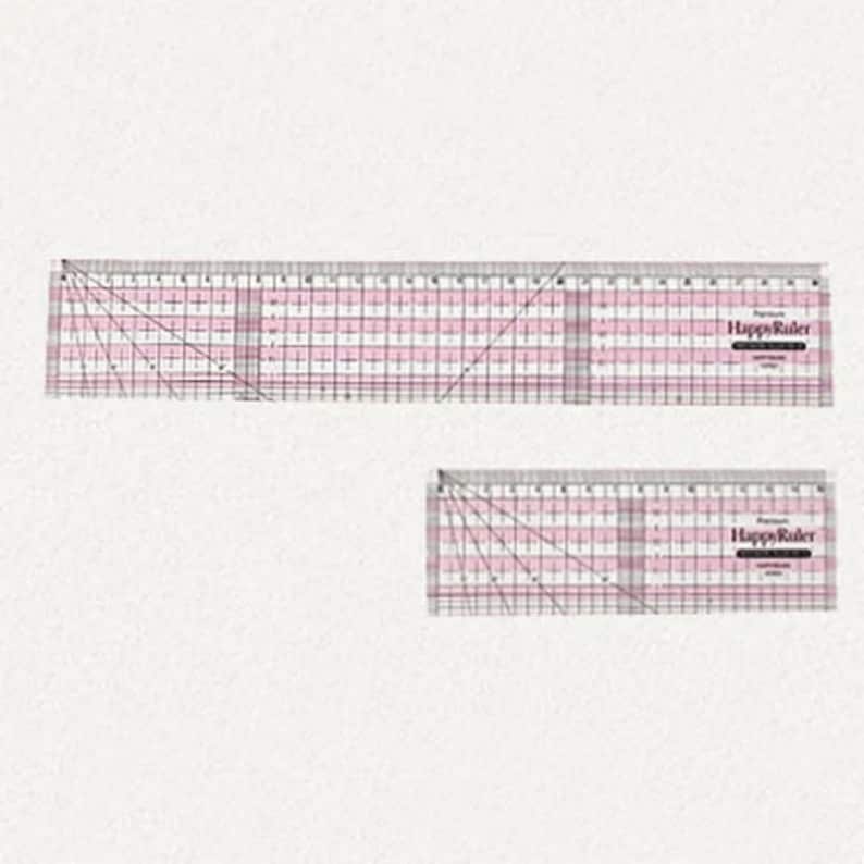 Puede incluir: Dos reglas de acolchado de acr&iacute;lico transparente con l&iacute;neas de cuadr&iacute;cula rosas y marcas diagonales. La regla m&aacute;s grande mide aproximadamente 30 cm de largo, y la m&aacute;s peque&ntilde;a mide unos 15 cm. El texto "Happy Ruler" est&aacute; impreso en cada regla.