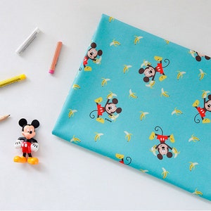 Peut inclure: Un tissu turquoise avec un motif répété de Mickey Mouse et de bananes jaunes. Le tissu est parfait pour les projets d'artisanat, le quilting et la couture.