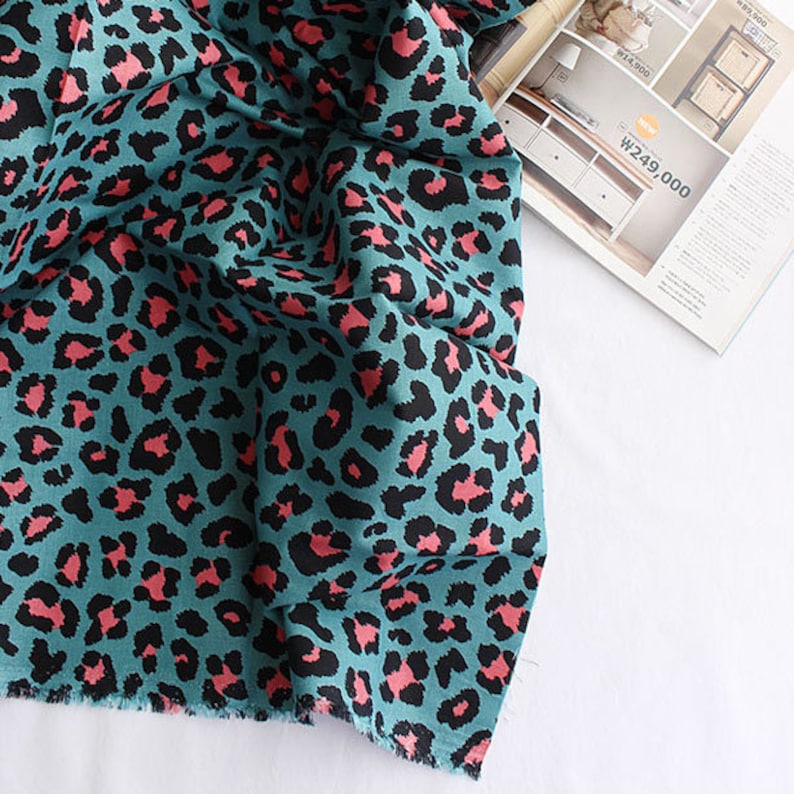 May include: Teal fabric with a pink leopard print pattern.