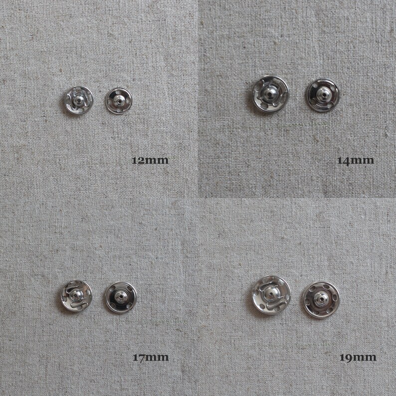 May include: Four sets of silver metal snap fasteners in different sizes: 12mm, 14mm, 17mm, and 19mm. The snaps are arranged in rows on a light grey fabric background.