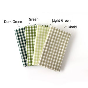 May include: Four folded fabric swatches in shades of green and khaki, arranged from dark green to khaki. Each swatch features a classic gingham check pattern. The labels above the swatches read "Dark Green", "Green", "Light Green", and "khaki".