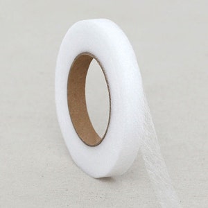 May include: A roll of white tulle ribbon with a cardboard core. The ribbon is soft and translucent, ideal for crafting, sewing, or decorating. The tulle is rolled into a compact form, ready for use in various projects.