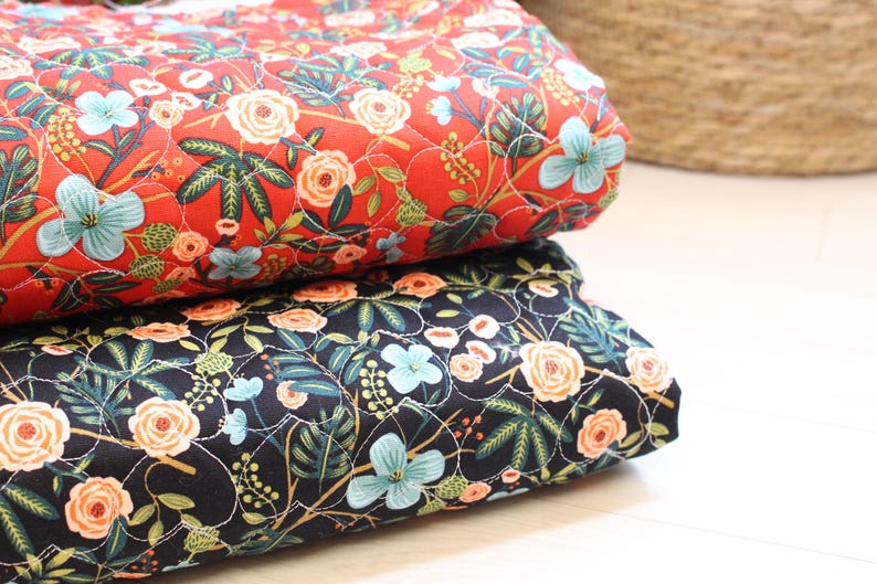 Pu&ograve; includere: Due pezzi di tessuto trapuntato piegati impilati l'uno sull'altro. Il pezzo superiore &egrave; rosso con un motivo floreale di fiori azzurri e color pesca con foglie verdi. Il pezzo inferiore &egrave; nero con lo stesso motivo floreale e cuciture bianche.