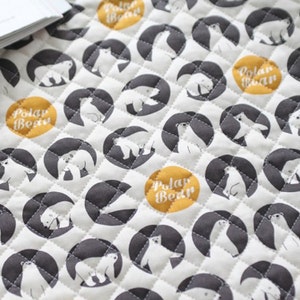 May include: White fabric with a repeating pattern of black circles containing white polar bears and yellow circles with the text "Polar Bear".