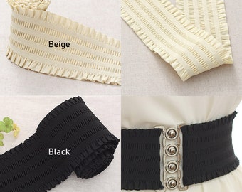 May include: Two rolls of elastic trim with ruffled edges. One roll is beige and the other is black. The trim is shown being used as a belt with a silver buckle.