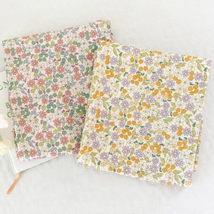 Könnte beinhalten: Zwei Stoffquadrate mit einem Blumenmuster. Ein Quadrat hat einen hellrosa Hintergrund mit grünen und rosa Blumen. Das andere Quadrat hat einen cremefarbenen Hintergrund mit lila und gelben Blumen.