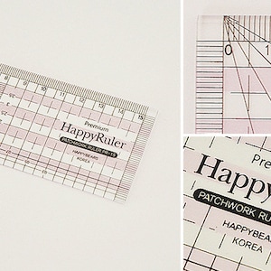 Puede incluir: Una regla de patchwork HappyRule de pl&aacute;stico transparente con l&iacute;neas de cuadr&iacute;cula rosas y medidas en cent&iacute;metros. La regla tiene l&iacute;neas diagonales y el texto "HappyRuler" y "HAPPYBEARS KOREA".