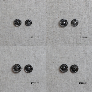 May include: Four black metal snap fasteners in different sizes: 12mm, 14mm, 17mm, and 19mm. The fasteners are arranged in two rows of two, with the largest fastener on the right.