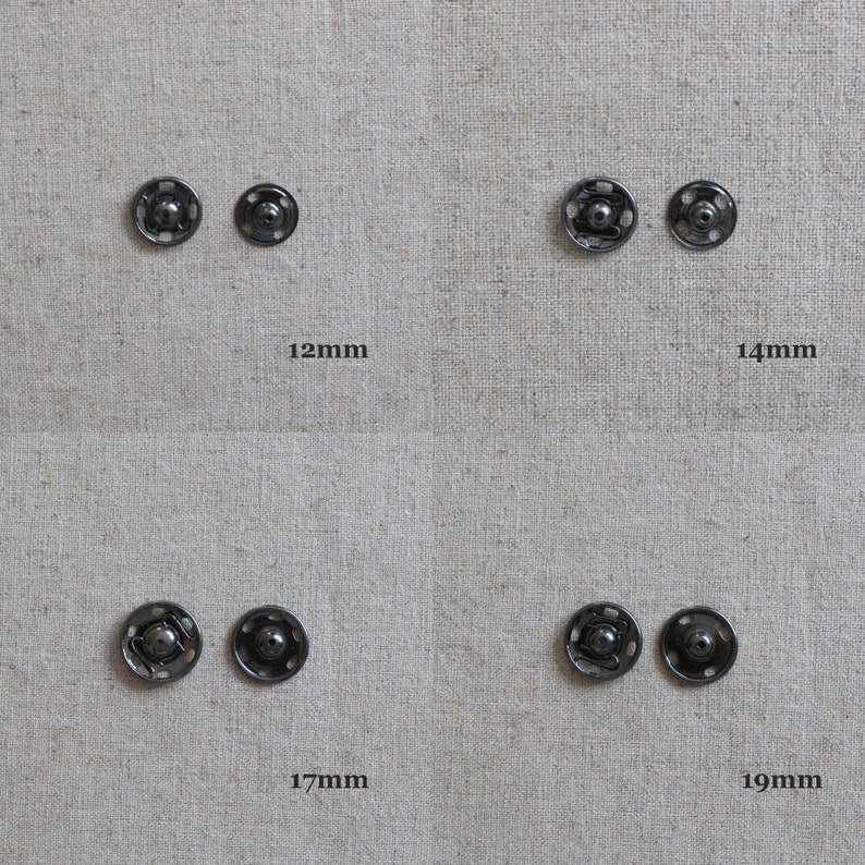May include: Four black metal snap fasteners in different sizes: 12mm, 14mm, 17mm, and 19mm. The fasteners are arranged in two rows of two, with the largest fastener on the right.