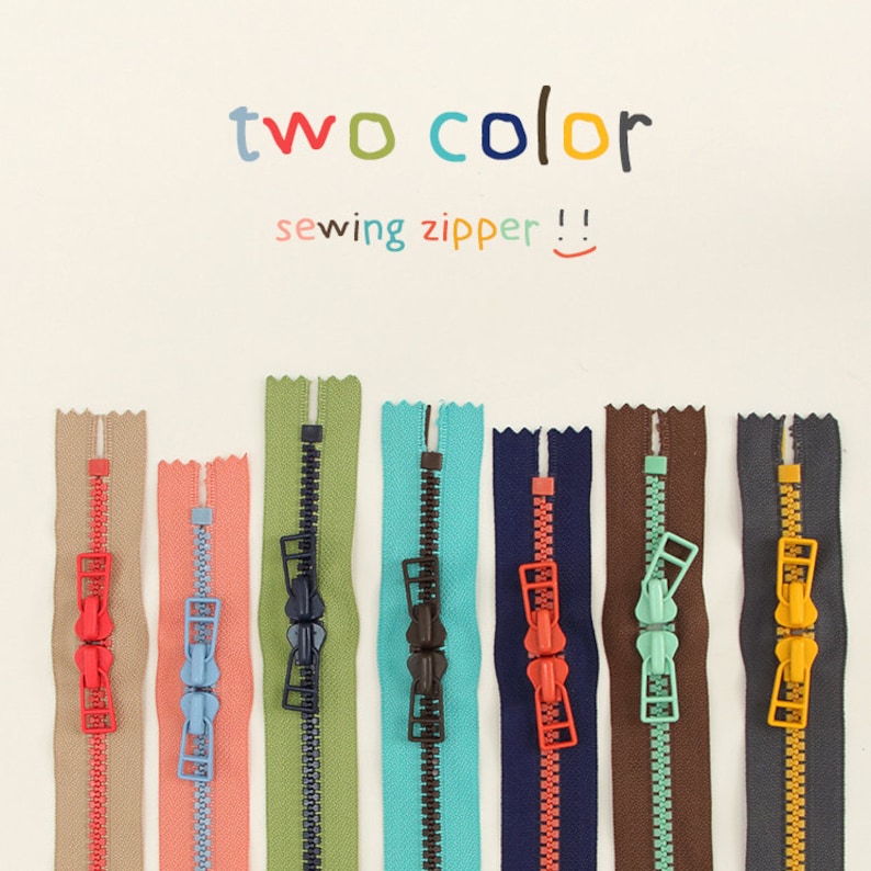 May include: Assortment of two-tone sewing zippers in various colors, including beige, coral, green, teal, navy, brown, and gray. The zippers have a metal slider and are labeled "two color sewing zipper!"