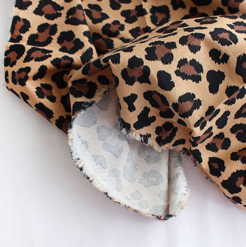 May include: Close-up of a brown and black leopard print fabric with a white and gray leopard print fabric underneath.