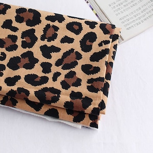 May include: A folded fabric with a leopard print pattern in shades of brown, black, and beige.