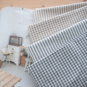 May include: Four fabric swatches in different patterns: a brown and white gingham, a blue and white stripe, a grey and white gingham, and a brown and white stripe.