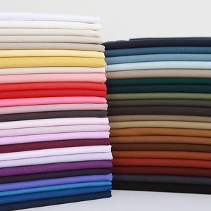 May include: A stack of fabric swatches in various colors, including white, beige, yellow, pink, red, brown, green, blue, and gray.