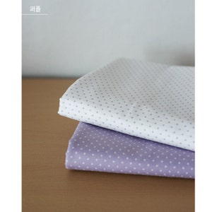 May include: Two folded pieces of fabric stacked on top of each other. The top piece is white with small purple polka dots, and the bottom piece is light purple with small white polka dots. The text "퍼플" is visible in the top left corner.