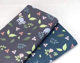 May include: Two folded pieces of fabric featuring a repeating pattern of sloths, green leaves, and small pink flowers. One piece is dark charcoal gray, and the other is a deep blue. The fabric displays a smooth, woven texture with a matte finish.