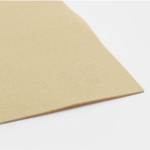 K&ouml;nnte beinhalten: Nahaufnahme einer beige Filzplatte. Der Filz ist glatt und hat eine dezente Textur.