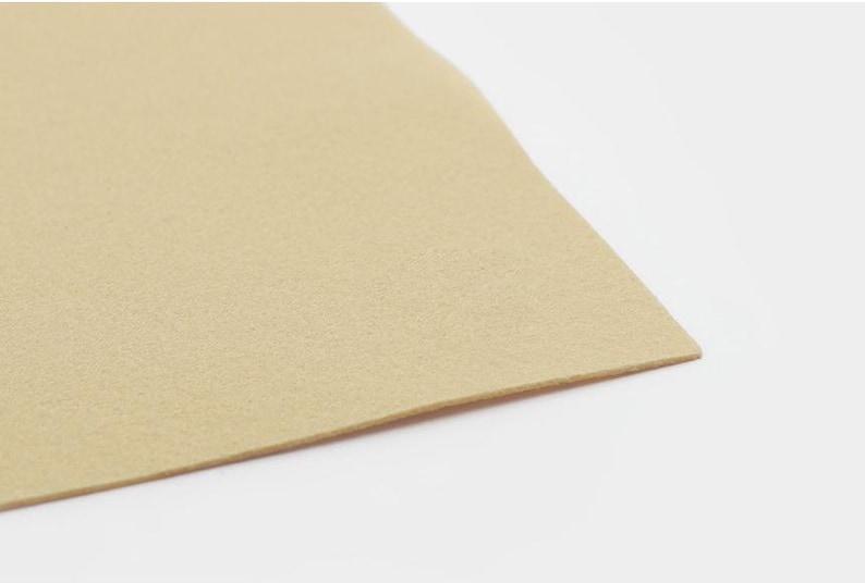 K&ouml;nnte beinhalten: Nahaufnahme einer beige Filzplatte. Der Filz ist glatt und hat eine dezente Textur.