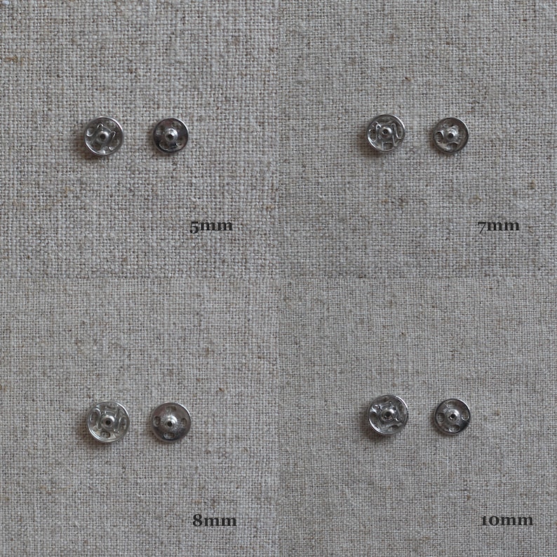 May include: Four silver metal snap fasteners in different sizes: 5mm, 7mm, 8mm, and 10mm. The fasteners are displayed on a beige fabric background.