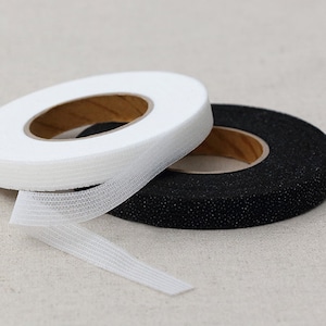 May include: Two rolls of white and black fabric tape. The tape is used for sewing and crafting.