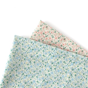 Peut inclure: Deux morceaux de tissu avec un fond blanc et un petit motif floral. Un tissu a des fleurs bleues et l'autre a des fleurs roses.