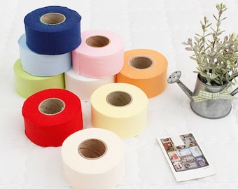 May include: Assortment of colorful rolls of paper tape, including red, orange, yellow, pink, light blue, green, and navy blue. The rolls are arranged in a pyramid shape on a white surface.  Made in South Korea.