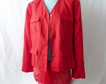 May include: A red linen blazer with a V-neck and multiple pockets. The blazer is worn over a red sheer scarf.