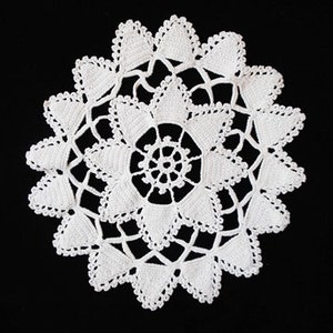 May include: White crocheted doily with a delicate floral design. The doily is circular and has a center with a smaller, more intricate design.