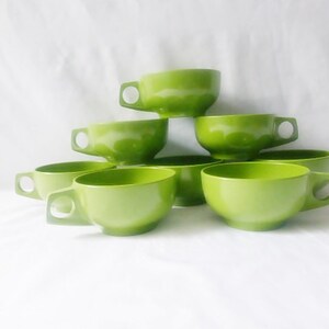 May include: Set of six green ceramic mugs with rounded handles. The mugs are stacked in a pyramid shape.