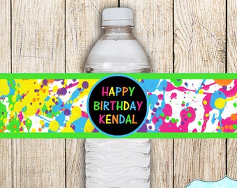 Puede incluir: Etiqueta de botella de agua con un diseño de salpicaduras de pintura coloridas. La etiqueta dice "Happy Birthday Kendal" en un círculo negro.