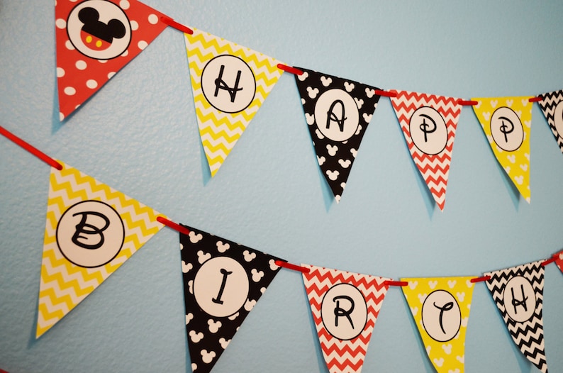 May include: A red, yellow, and black banner with Mickey Mouse ears and the words "Happy Birthday" in white letters.